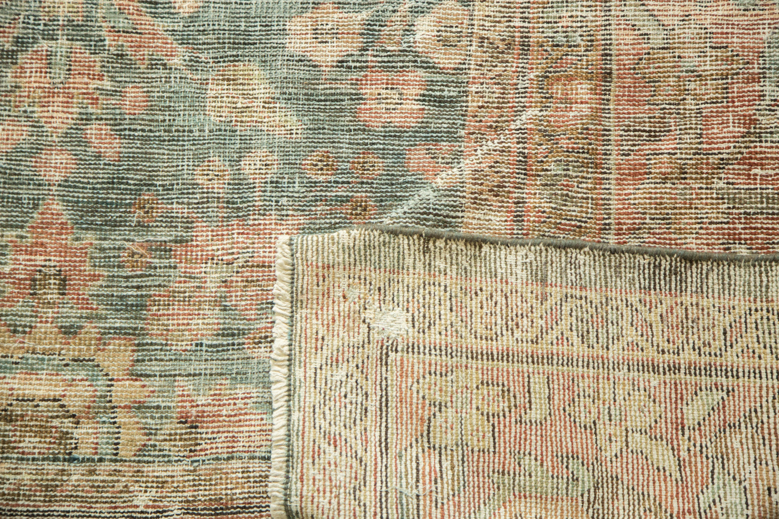 Distressed Mahal carpet pile in dusty teal and faded red, showing mostly even wear and restrung foundation.